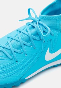 Lichtblauwe Nike voetbalschoenen met een gestructureerde synthetische bovenkant, platte veters en een witte swoosh-logo aan de zijkant.