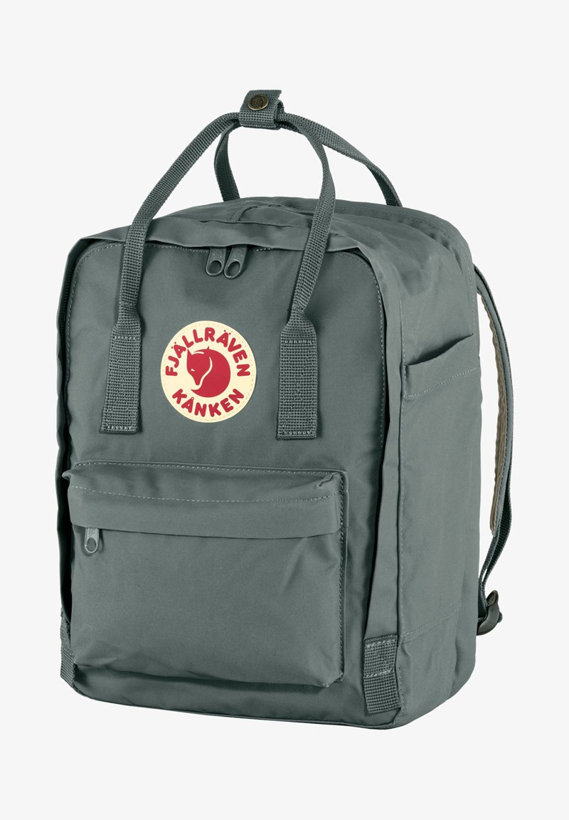 Mochila Kanken gris de Fjällräven, hecha de tela duradera, con bolsillo frontal, asa superior y tirantes ajustables. Logo circular en la parte frontal.