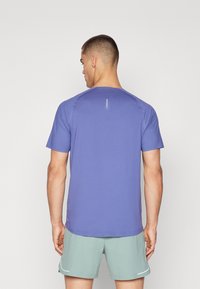 Kortærmet atletisk T-shirt i blødt, let purpurfarvet stof. Har en rund hals, glat tekstur og minimal designdetalje på bagsiden.