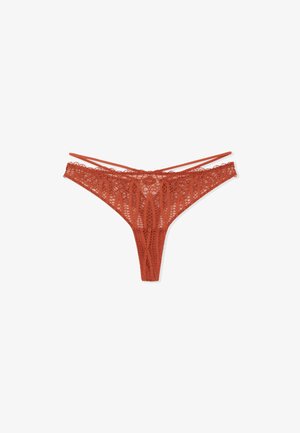 String rouge en dentelle avec un motif floral, des bretelles fines et une forme triangulaire. Détails délicats tout au long avec une texture lisse.