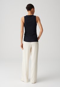 Top senza maniche blu navy con un design aderente, abbinato a pantaloni larghi color crema. Tessuto liscio, stile semplice e senza pattern visibili.
