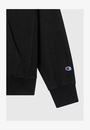 Manica di felpa nera con polsino a costine e piccolo logo Champion ricamato in blu, rosso e bianco vicino al polso.