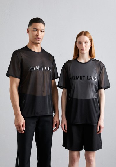 Schwarze Mesh-T-Shirts mit reflektierendem "HELMUT LANG"-Logo, getragen mit schwarzen Sportshorts/-hosen. Minimalistisches Design, leichtes Material, entspannte Passform.