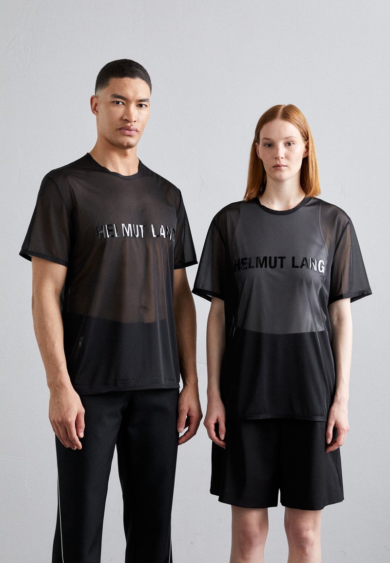 Must mustri T-särgid, millel on peegeldav "HELMUT LANG" logo, kantud mustade sportlike lühikeste/ pikkade pükstega. Minimalistlik disain, kerge materjal, lõdvestunud istuvus.