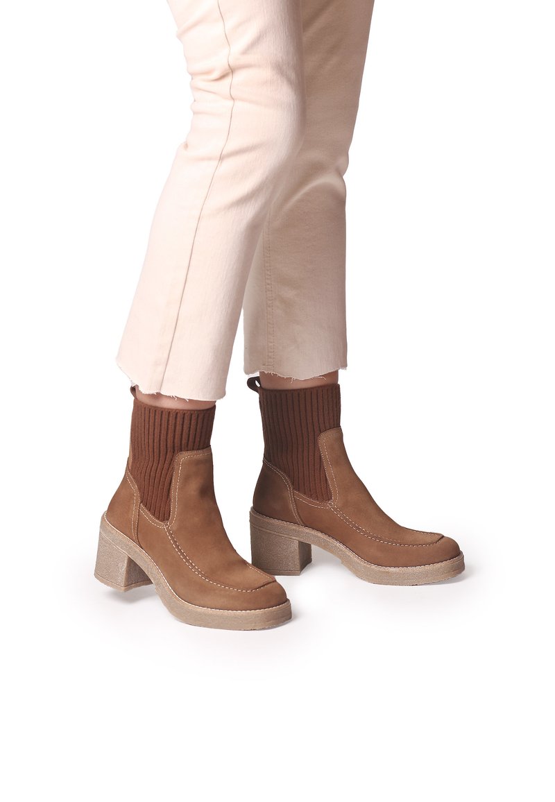 Stivaletti alla caviglia in suede marrone con polsini in maglia elastica, punta tonda e tacchi grossi; cuciture beige a contrasto e suola testurizzata.