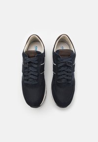 Tumši zili sneakers ar zamšādas un sieta augšdaļu, ar auklām, baltām akcentēm un brūna ādas detaļām uz papēža.