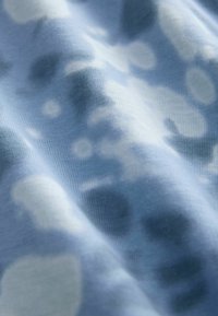 Light blue fabric with soft texture, featuring abstract light and dark patterns, showing natural folds and a smooth finish.