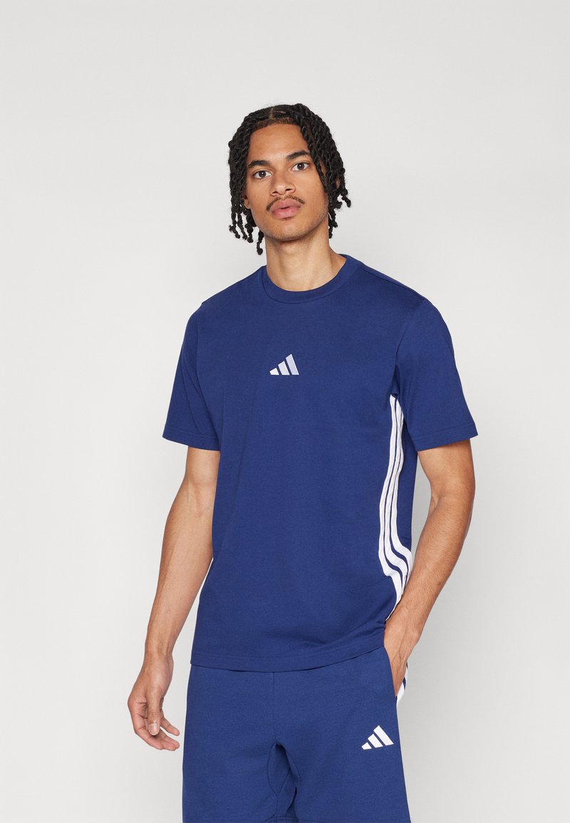 T-shirt bleu à manches courtes avec le logo Adidas sur la poitrine et des détails à trois bandes blanches sur les côtés. Matière en coton, coupe décontractée.