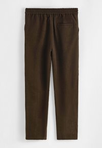 Pantalon marron extensible avec une ceinture, doté d'une poche arrière unique et d'une texture lisse. Le design est droit avec un style simple.