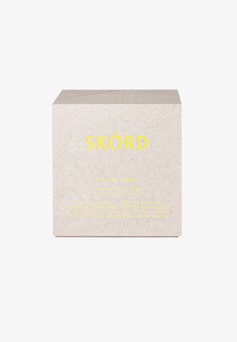 Quadratische Pappschachtel in Hellbeige mit gelbem Text. Enthält Branding, Produktinformationen und Duftbeschreibung. Minimalistisches Design.