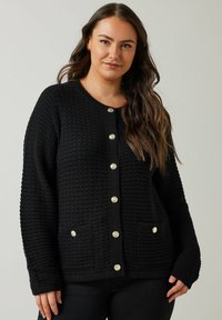 Zwart textuur cardigan met een ronde halslijn, gouden knopen aan de voorkant en twee voorzakken. Lange mouwen met geribbelde manchetten.