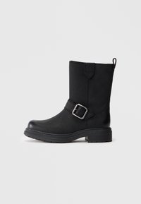 Black ankle boots with a smooth leather texture, featuring a decorative strap and silver buckle, robust rubber sole, and round toe design.