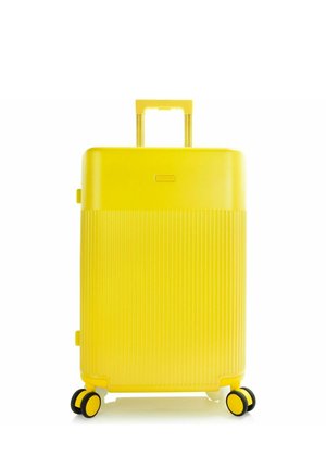 Valise rigide jaune vif avec moitié inférieure texturée, poignée rétractable et quatre roues doubles pivotantes sur fond blanc.