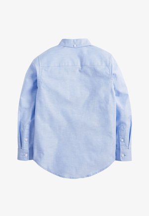 Világoskék, hosszú ujjú ing hegyes gallérral, gombos zárással, lekerekített alsó résszel és mandzsettagombokkal. Simább anyag, enyhe fényességgel.