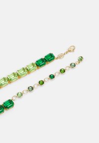 Brățară de nuanță aurie, cu pietre rectangulare și rotunde verzi și verde deschis, legate cu accente metalice și un închizător de tip homar.