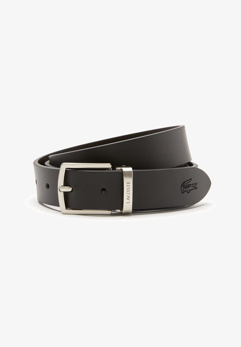 Cinto de couro preto com fivela de metal prateada, apresentando um pequeno logotipo da Lacoste em relevo na tira e furos espaçados uniformemente para ajuste.
