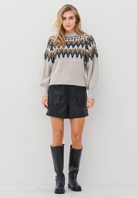 Jasnoszara, dziana sweter z czarnymi i brązowymi geometrycznymi wzorami, zestawiony z czarnymi skórzanymi szortami i czarnymi kozakami do kolan.
