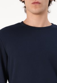 Marineblauwe crew-neck sweatshirt gemaakt van een soepele stof, met een geribbelde kraag en lange mouwen, met een eenvoudig, effen ontwerp.