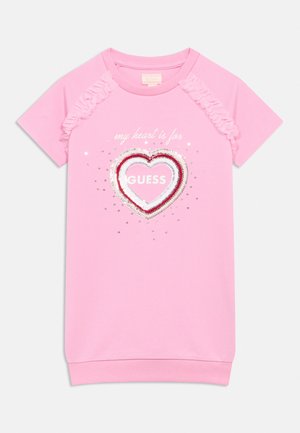 Różowa sukienka z krótkim rękawem i falbankami na ramionach, z cekinowym sercem i napisem "my heart is for GUESS" z przodu.