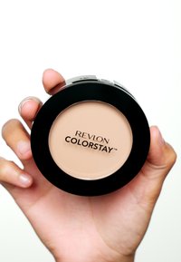 Rund kompakt av Revlon Colorstay-foundation, med en slät beige yta och svart plastkapsling, med varumärkeslogotypen tydligt visad.