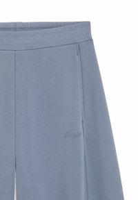 Light blue joggers made of soft fabric, featuring a waistband and side pockets, with subtle embroidered logo on the lower leg.