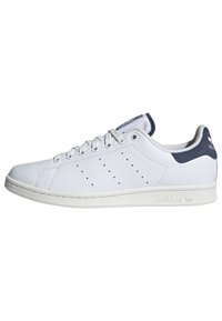 Scarpa sneaker Adidas Stan Smith bassa bianca con linguetta sul tallone blu navy, tre strisce forate, lacci bianchi e suola in gomma.