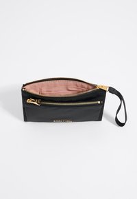 Black nylon pouch with gold-tone zipper and wrist strap, featuring a pink lining and brand logo on the front. Two zippered compartments.