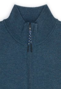 Granatowy sweter z dzianiny z wysokim kołnierzem i zamkiem błyskawicznym z przodu. Posiada fakturowany materiał oraz kontrastowy sznurek na suwak.