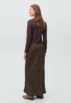 Haut marron à manches longues avec découpes aux épaules, associé à une jupe maxi en imprimé léopard marron, dotée d'une texture lisse et de bottes arrivant à la cheville.
