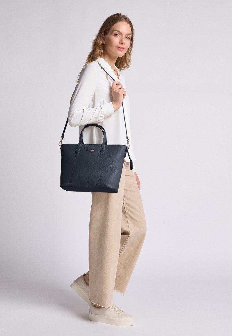 Bolso tote de piel azul marino con dos asas superiores y una correa de hombro desmontable. Presenta un acabado texturizado y un logo sutil en el frente.