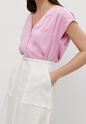 Haut rose clair à manches courtes, décolleté en V et détails froncés aux épaules, associé à une jupe en lin blanche avec poches avant.