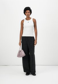 Débardeur blanc, pantalon large à motifs noirs, et un petit sac à main violet clair. Tissu texturé et designs contrastés.