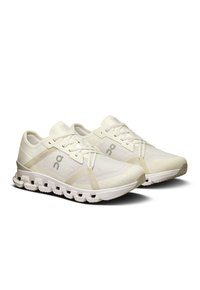 Light beige running shoes with a mesh upper, molded sole, and cushioned midsole. Features include a logo and distinctive lacing design.