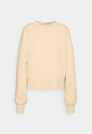 Felpa corta beige con maniche lunghe e leggermente a palloncino, colletto rotondo e polsini a coste. Realizzata in un morbido tessuto testurizzato.