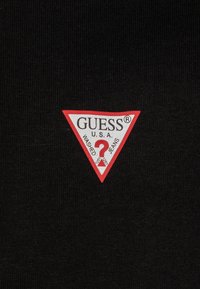 Fekete, rövid ujjú póló piros és fehér háromszög logóval, rajta a "GUESS U.S.A." és a "WASHED JEANS" felirat. Texturált anyag.