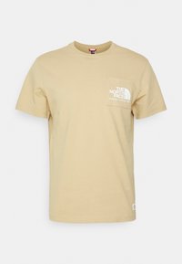 Beige tričko s krátkým rukávem a náprsní kapsou, na kterém je bílé logo "The North Face Berkeley, California 1966".