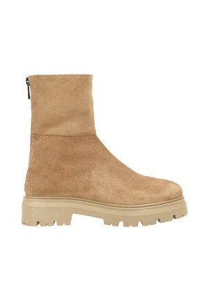 Bottine en daim beige avec tige lisse et semelle en caoutchouc épaisse. Dotée d'une fermeture éclair latérale et d'un bout arrondi. Finition texturée.