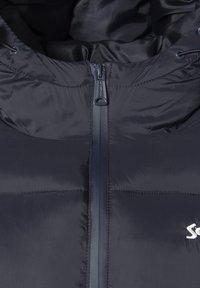 Veste matelassée bleu marine avec une fermeture éclair avant, une capuche ajustable à cordon de serrage et un design à panneaux cousus avec un accent de logo subtil.