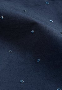 Marinfärgad tyg med en slät yta, prydd med utspridda glänsande blå rhinestones, vilket skapar en subtil kontrast och visuell intresse.