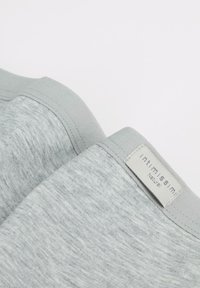Lichtgrijze stof met een licht gestructureerde afwerking, met een gladde tailleband en een label met de tekst "intimissimi Natura."