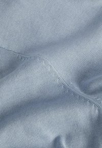 Lichtblauwe gebreide stof met een gladde textuur en zichtbare stiksels. De stof vertoont zachte, gelijkmatige patronen doorheen.