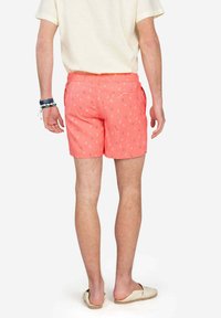 Pantalones cortos de color coral con un pequeño patrón de flores, hechos de una tela ligera, cuentan con una cinturilla estándar y bolsillos laterales.