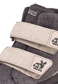 Stivale grigio in feltro con due cinghie in Velcro bianche. Presenta un'etichetta con logo e un motivo di animale impressa sulla cinghia. Dettagli in tessuto testurizzato visibili.