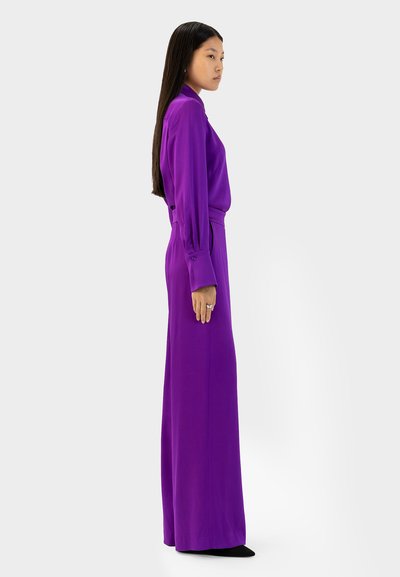 Paarse lange jurk met een aansluitende taille, vloeiende rok en knoopmanchetten. Gladde stof met een strakke silhouet en geen zichtbare patronen.