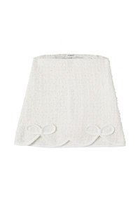 Gonna in tessuto bianco con texture, orlo a scallop e due fiocchi decorativi in fondo. Superficie morbida e soffice con una leggera lucentezza.