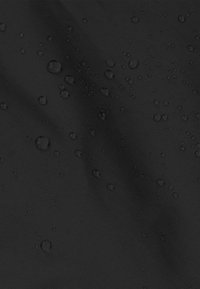 Schwarzer, strukturierter Stoff mit einer wasserfesten Beschichtung, auf dessen Oberfläche sichtbare Wassertropfen liegen. Die Oberfläche behält ein glattes Aussehen.