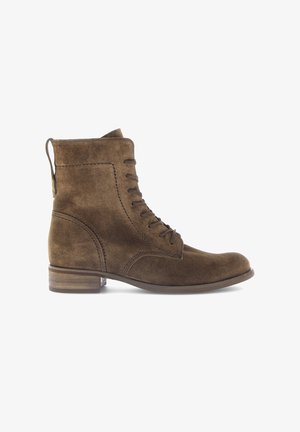 Stivaletti in suede marrone con design alla caviglia, lacci, punta rotonda e tacco basso impilato. Dotati di una linguetta per facilitare l'indossamento.
