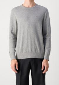 Harmaa neulepusero, jossa pitkät hihat, pyöreä pääntie ja resorireunaiset hihansuut. Edessä pieni kirjailtu logo. Sileä pinta.