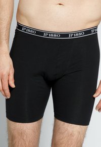 Černé boxerky vyrobené z hladké látky s přiléhavým střihem. Mají široký elastický pas s bílým nápisem "JP1880".
