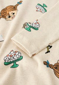 Kremowy żebrowany materiał z zabawnymi ilustracjami ciast na zielonych stojakach oraz rysunkowymi twarzami, z kontrastującymi czarnymi i kolorowymi akcentami.